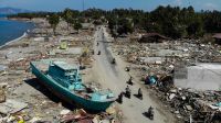 People drive past a washed up boat and collapsed buildings in Palu on October the 1st, 2018, after an earthquake and tsunami hit the area on September 28th.