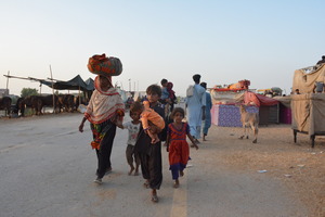 A family walks in a displacement camp. © Development Tales Media / HI