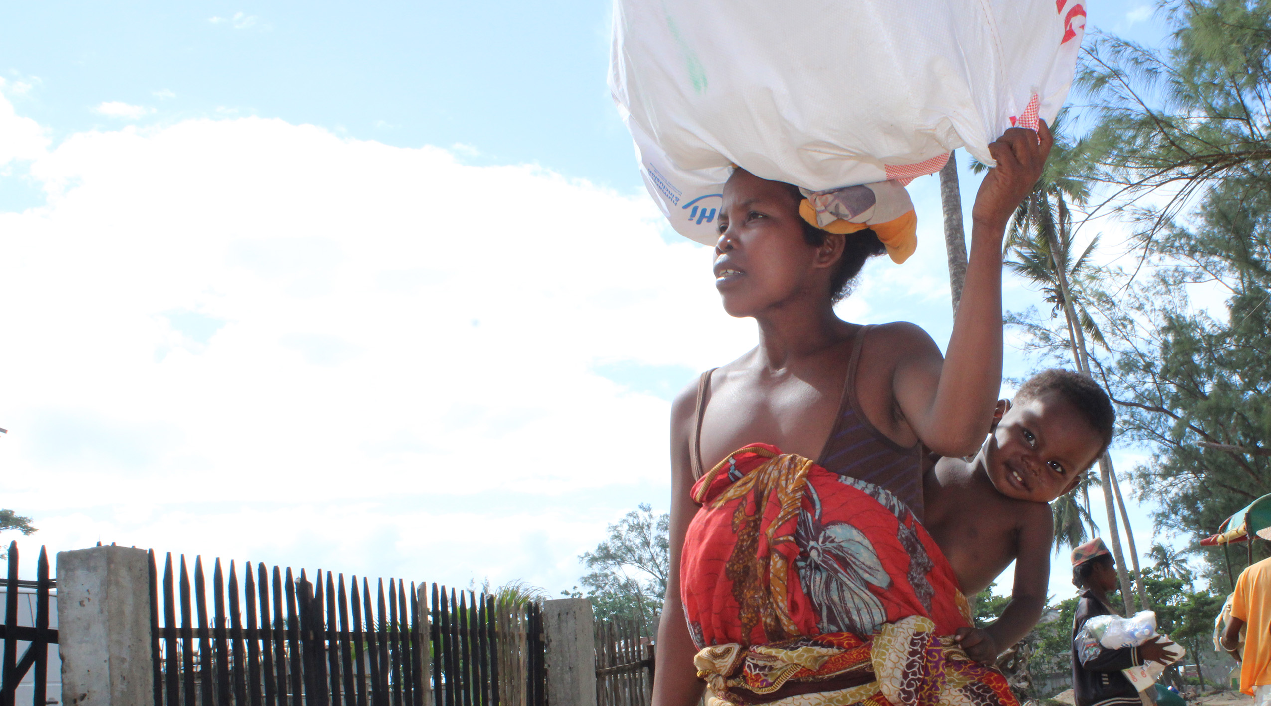 Marie Antoinette walks with her HI supply kit and holds one of her children. ©H.Andrianjatovo / HI