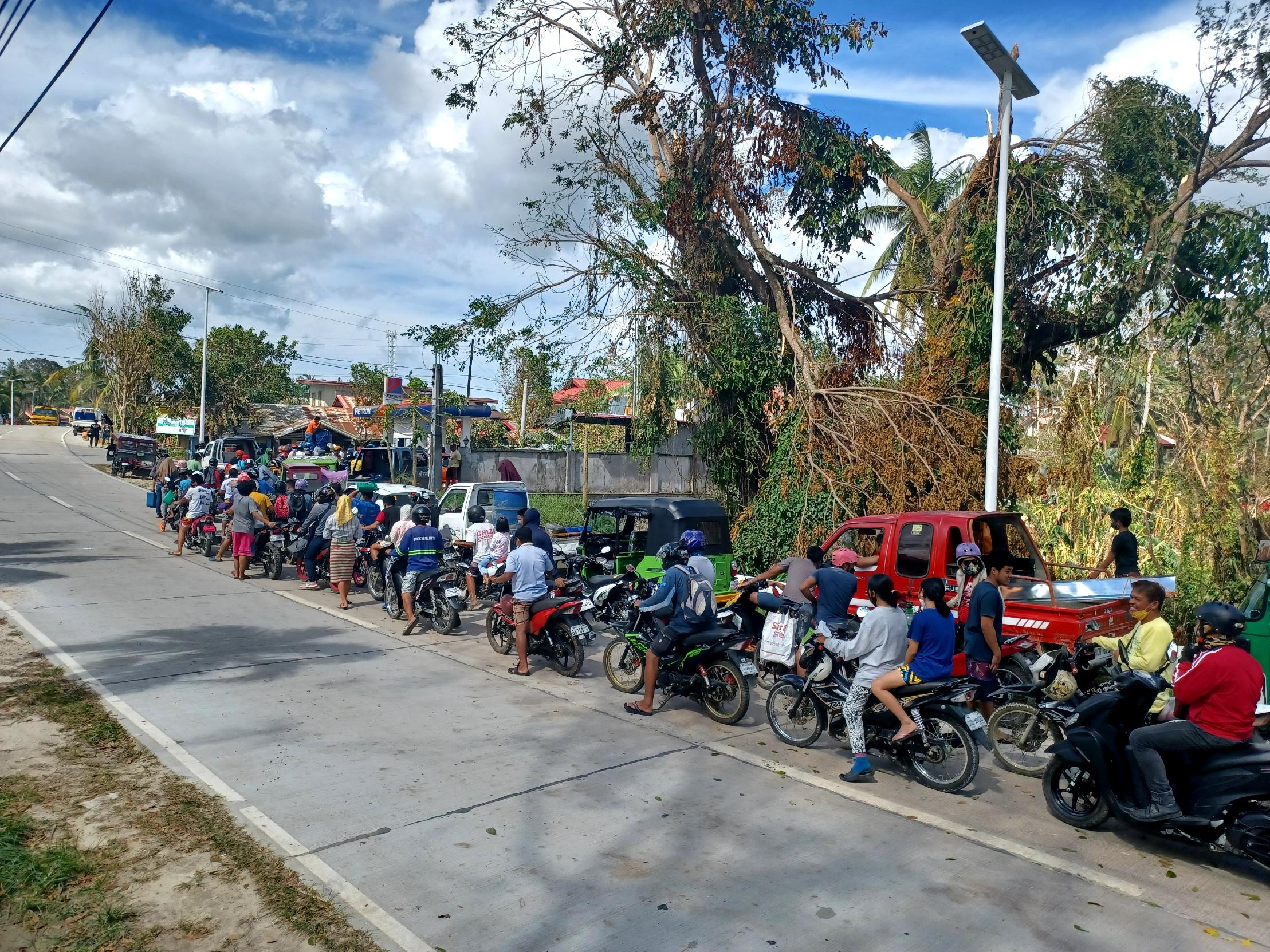 ©A.Dumduma/HI. A line of people extends into the street to buy gasoline after typhoon RAI.