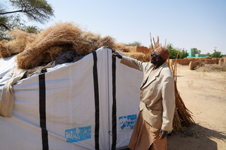 Ali Naino shows his year’s harvest drying beneath the roof of his tent. © J. Labeur / HI