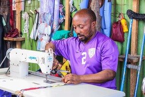 Christian Ngongo, a refugee from the Congo, making a garment in his sewing workshop. © Imani Rugenge / HI