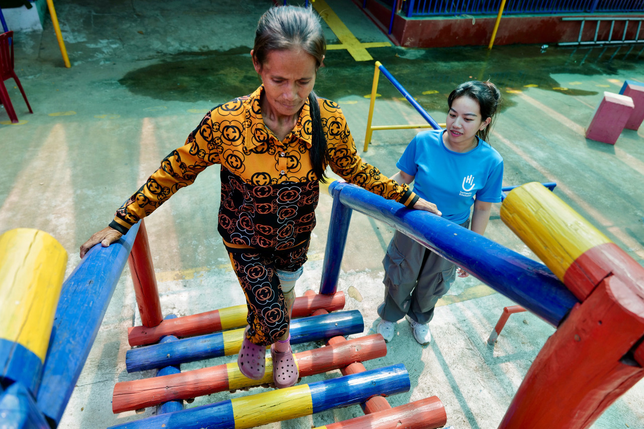 A woman who has had a prosthesis climbs a staircase accompanied by a physiotherapist from H
