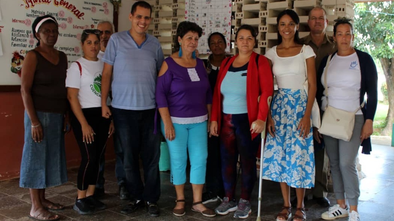 Seven people stand next to each other in a room, smiling at the camera.