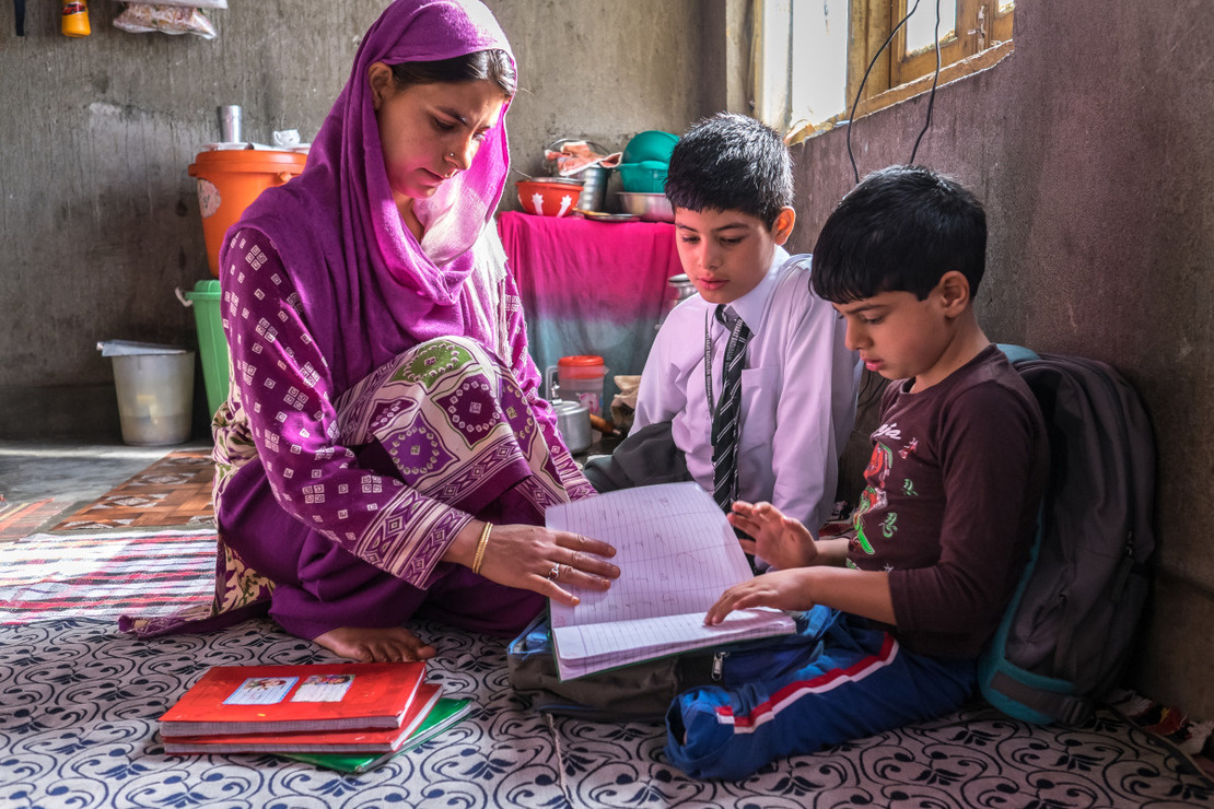 A mother sitted near her son with a schoolbook 