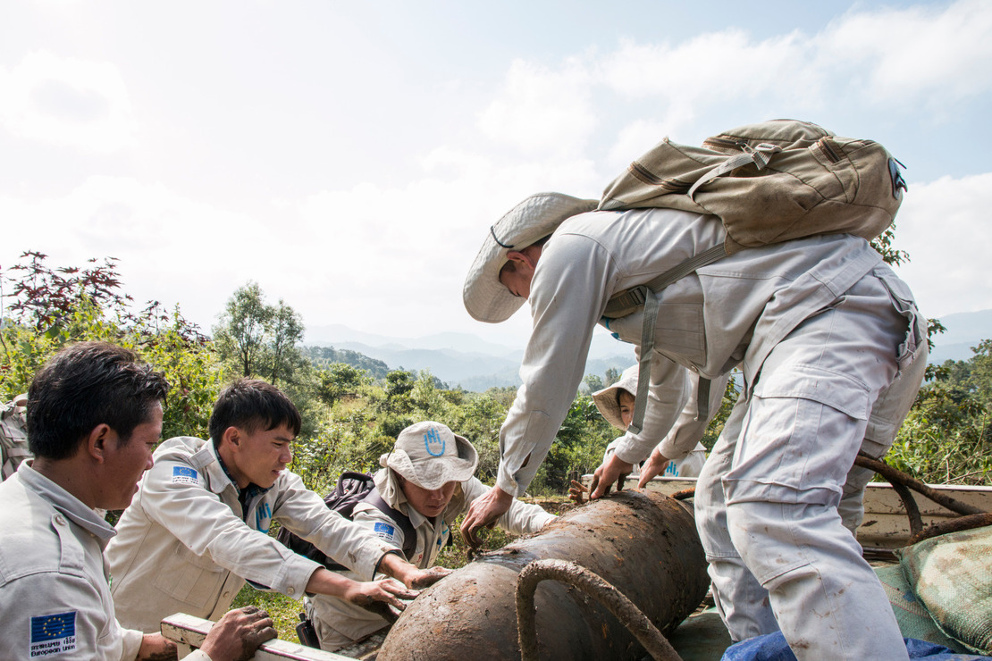 Deminers lift a huge shell together to place it in the lorry