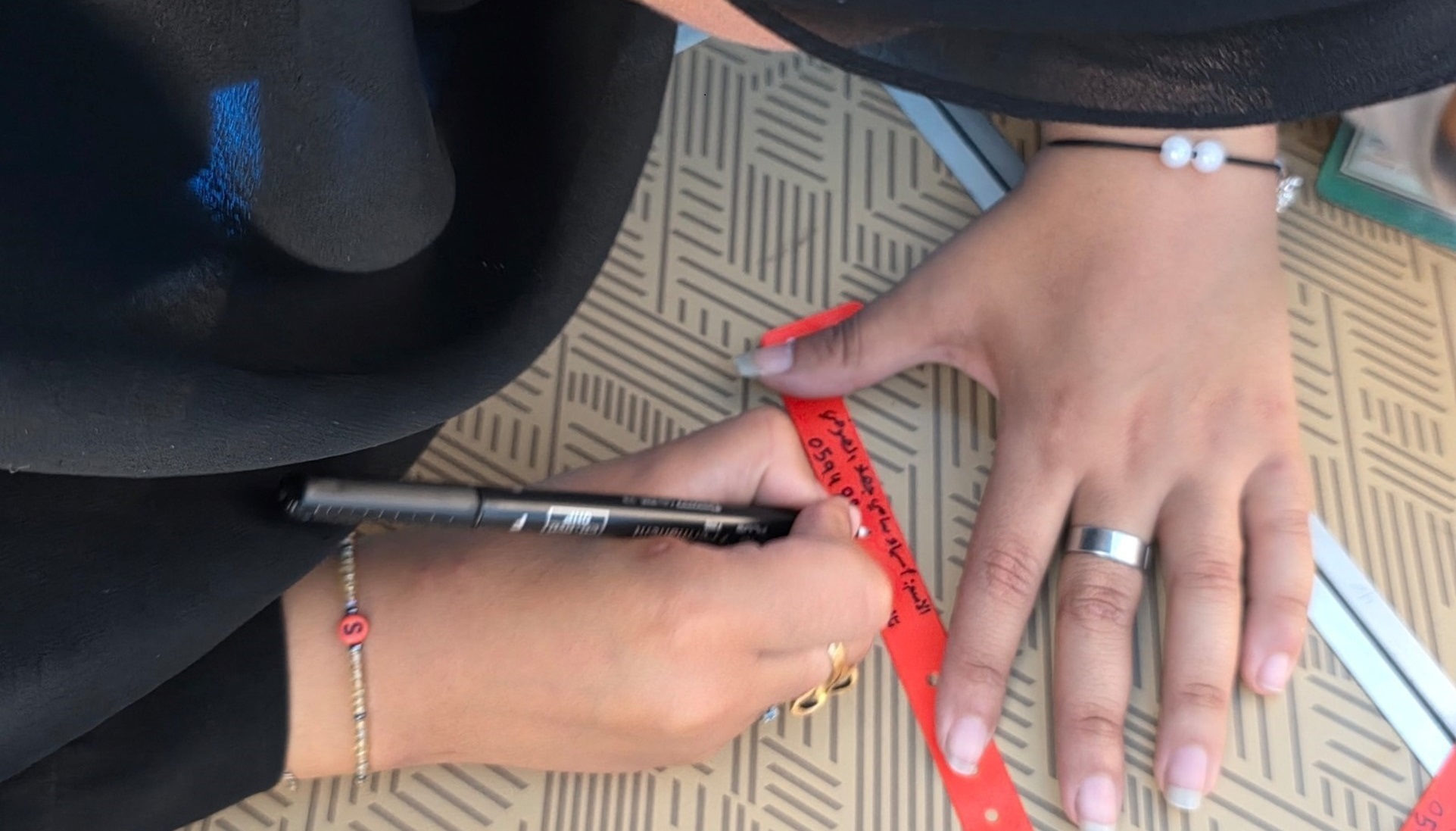 A mother write her phne number on an ID bracelet