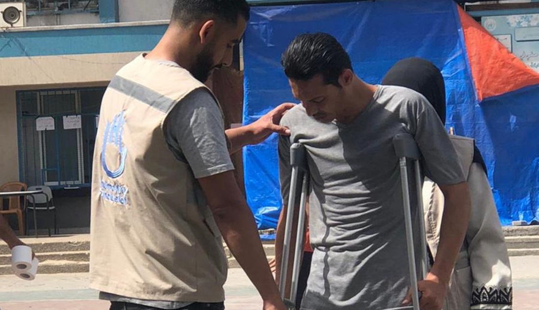 Haitham in a displaced camp, helping a beneficiary
