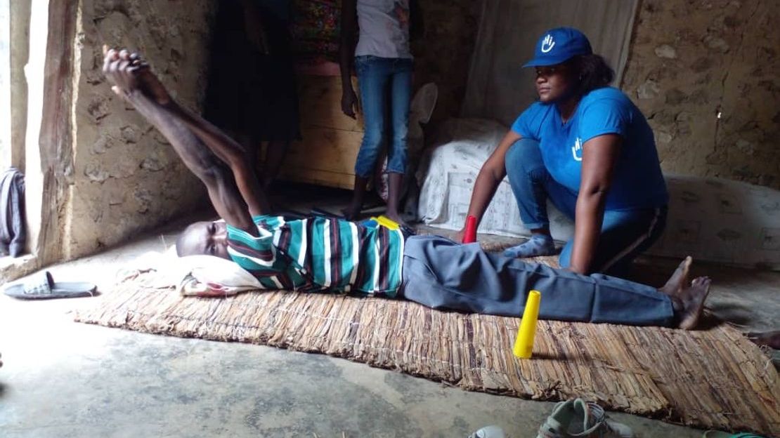 Jérôme doing his rehabilitation exercises at home, helped by members of HI’s mobile teams. 