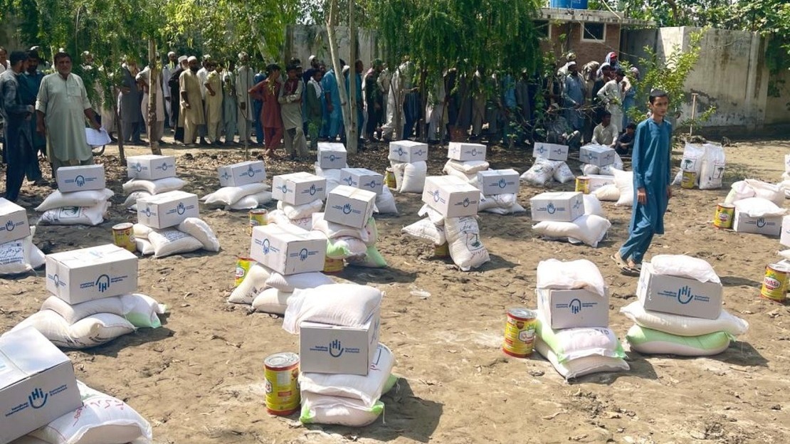 HI food provisions sit on the ground as beneficiaries wait in line to receive their kits. 