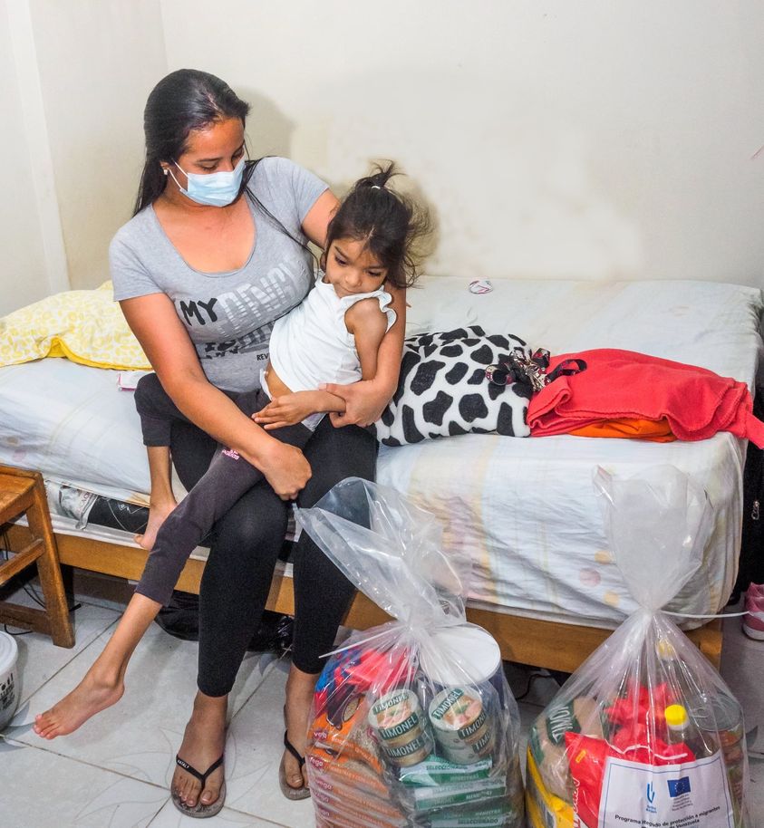 Luisa carrying her daughter Alicia and the food baskets donated by HI.