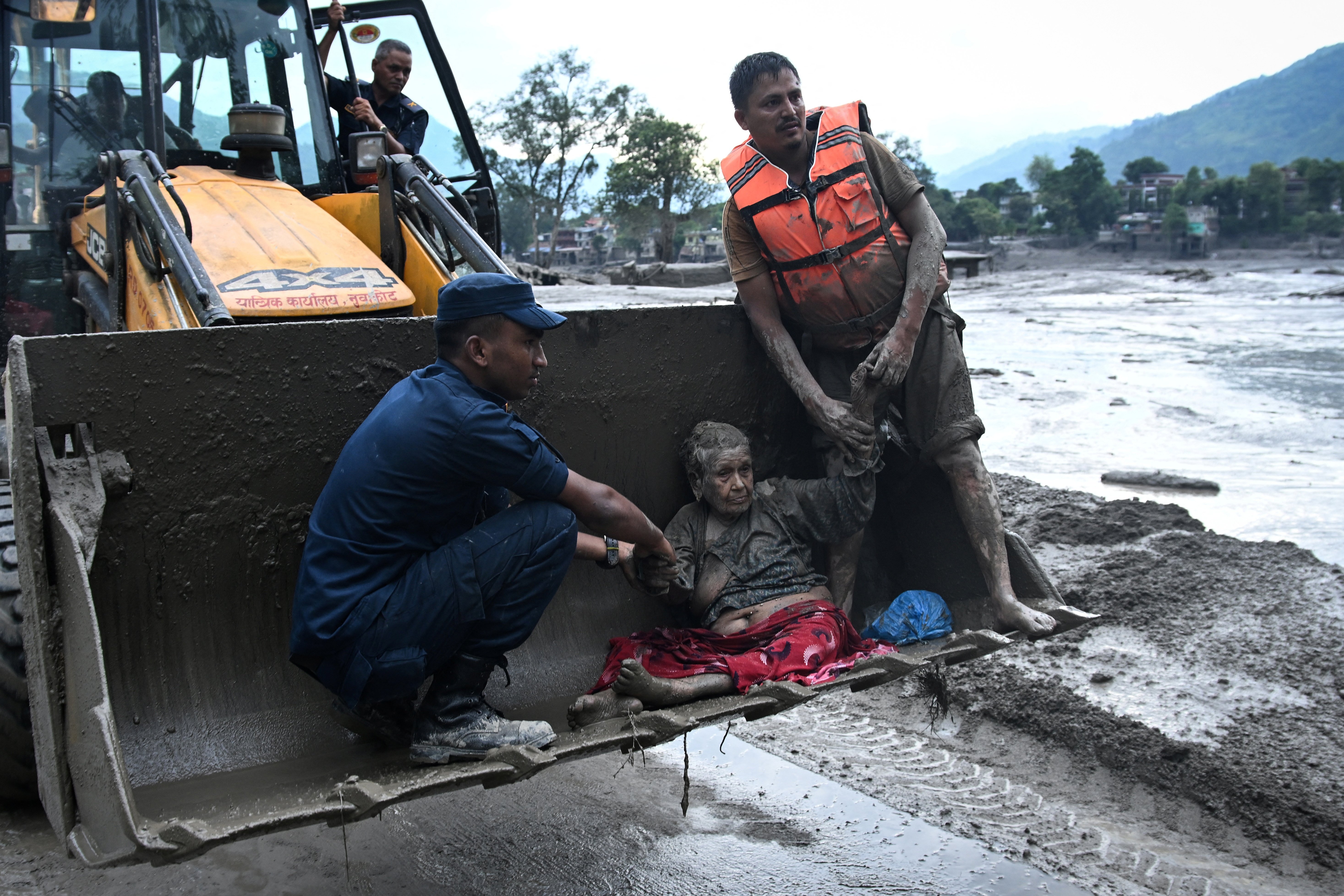 Rescuers help a flood survivor, following flash floods and a landslide in Nepal's Nuwakot district in August 2026. © PRAKASH MATHEMA / AFP
