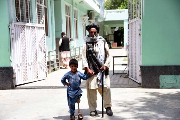 Sanaullah, 5, standing with his father outside the rehabilitation centre in Kandahar. He lost his leg to a mortar in Afghanistan.