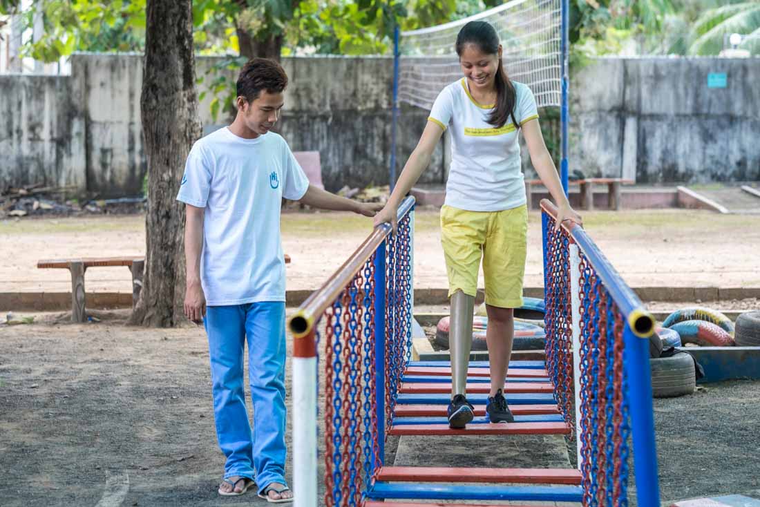 A girl with a prosthetic leg walks across an obstacle in HI' rehabilitation centre, Cambodia