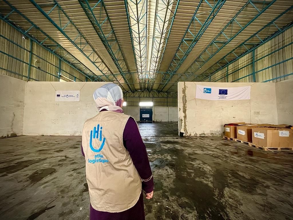 A femal HI staff stands with her back to the camera in HI's warehouse in Rafah, Gaza, before its destruction. April 2024 