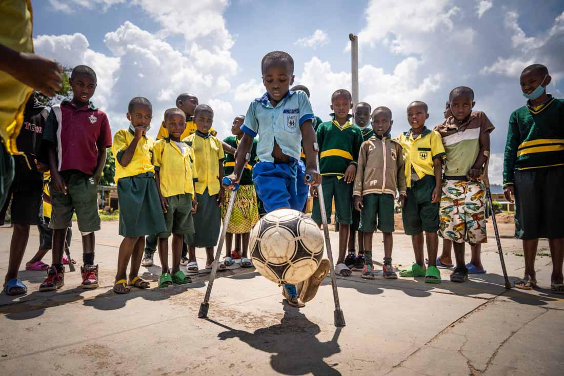 Longini playing football in the courtyard at school after he received his new prosthetic legs, Rwanda
