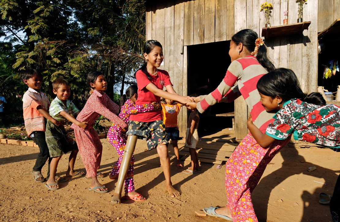 A 13 year old girl who is wearing a prosthetic leg is doing a tug of war with her friends in Cambodia