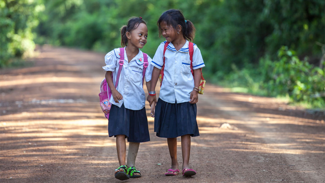 Channa, a young amputee supported by HI, on her way to school with a friend in Cambodia. 