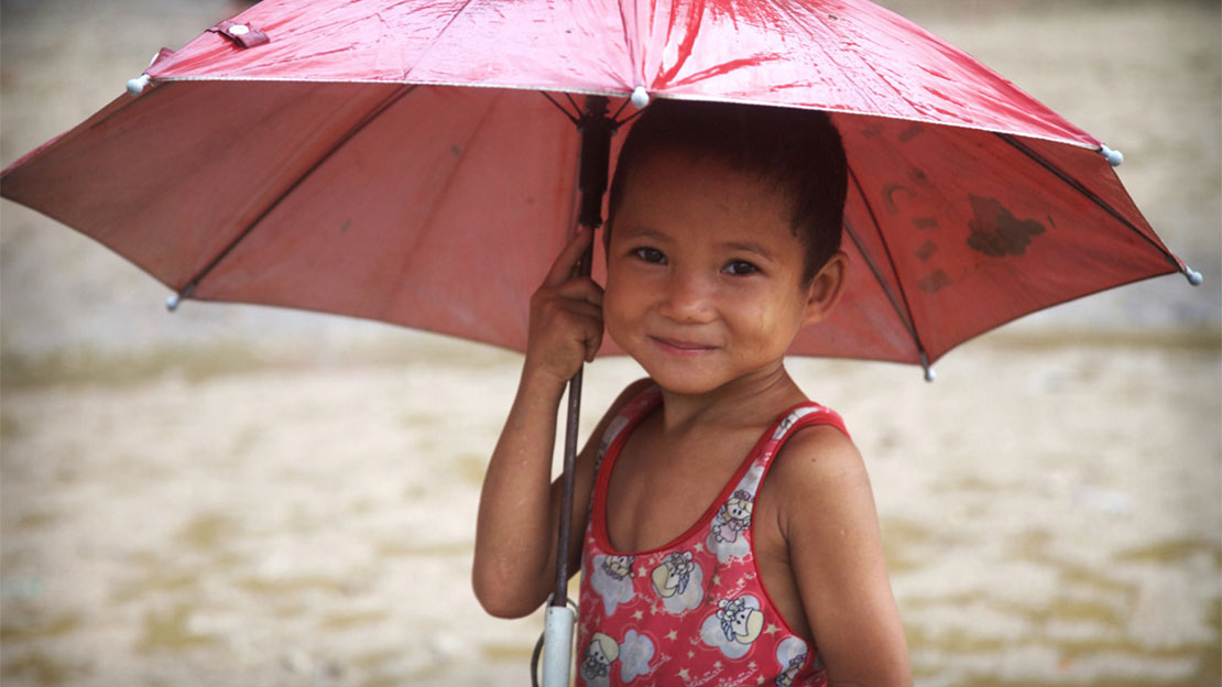 A child with an umbrella in Mae La refugee camp.