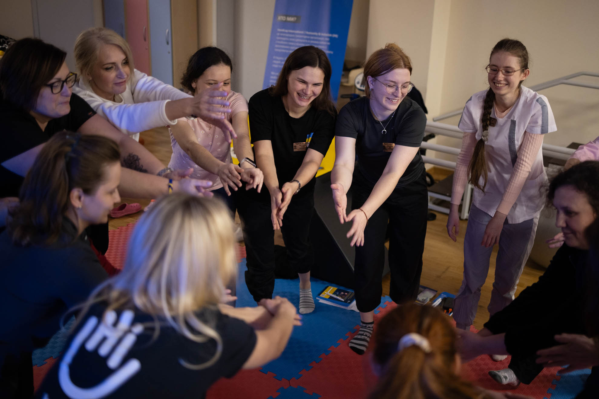 A group of women are in a circle and putting their hands together.