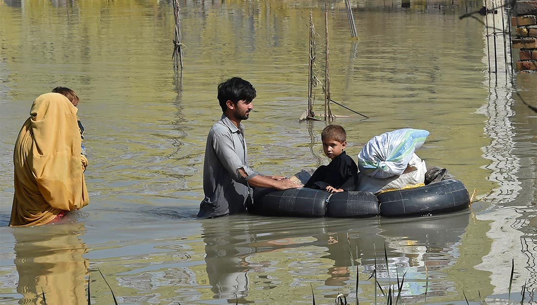  A family wades through a flood hit area following heavy monsoon rains in Charsadda district of Khyber Pakhtunkhwa on August 29, 2022.