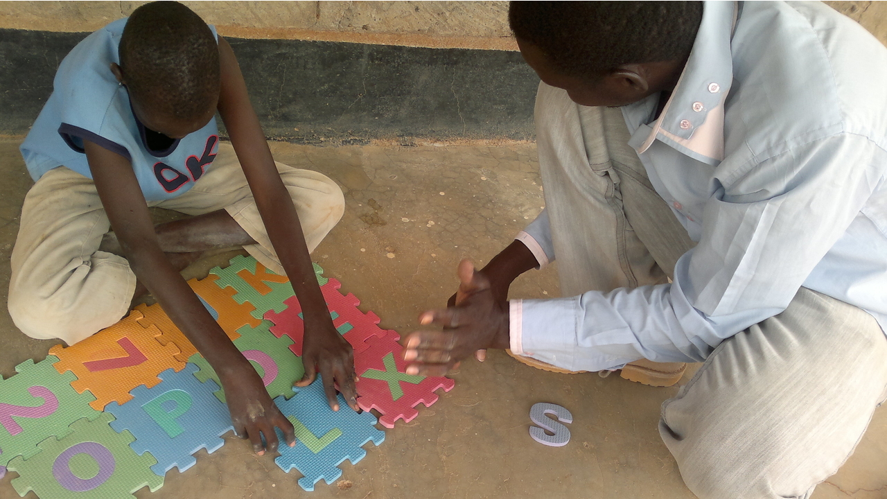 A child with his father doing puzzle during a psychomotor development session in the Dadaab camp, Kenya; }}