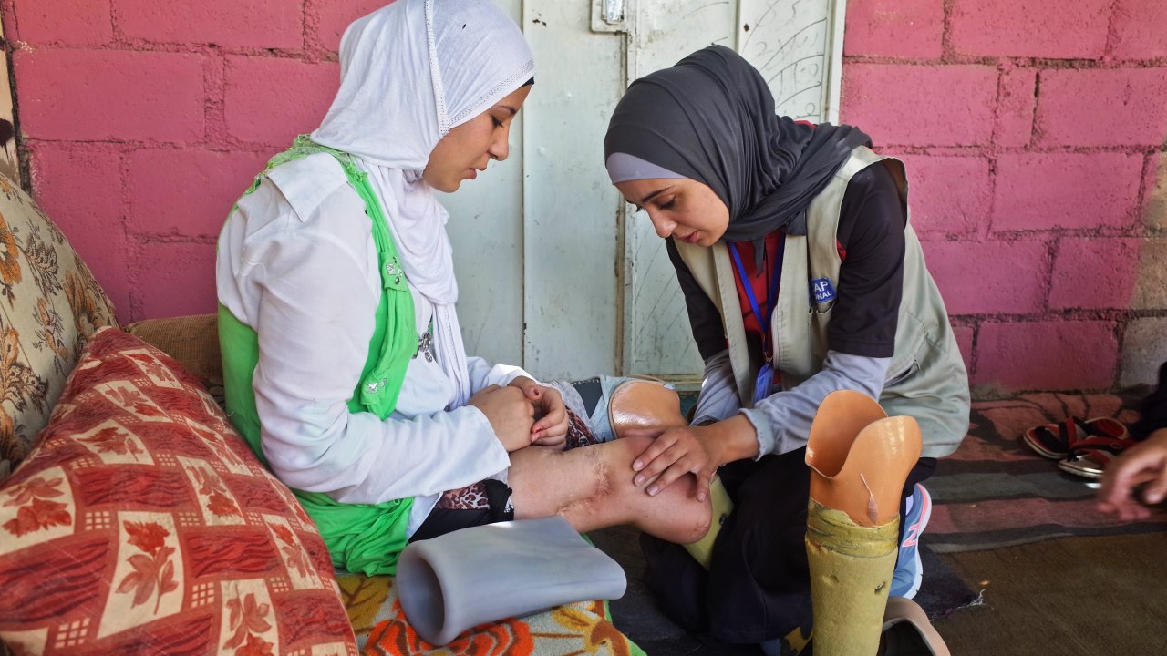 Salam has her legs checked by a Handicap International physiotherapist; }}