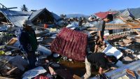 Indonesian men search for a family member at their damaged house in the Balaroa village in Palu, on October 1st, 2018, after an earthquake and tsunami hit Indonesia on September 28th.