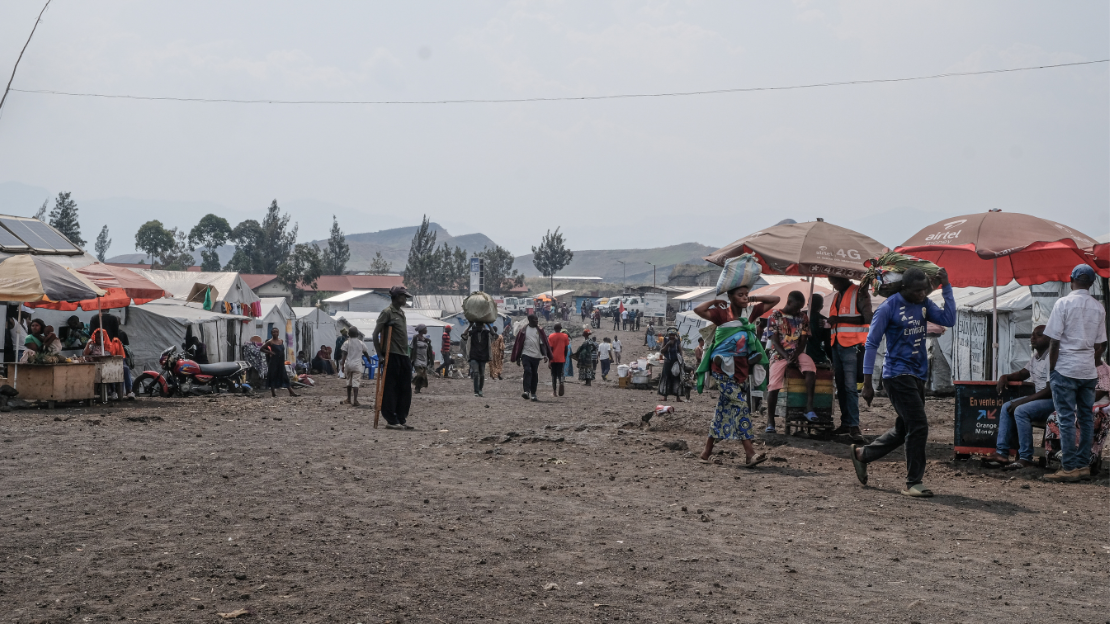 Overview of a street with passers-by and tents lining it.; }}