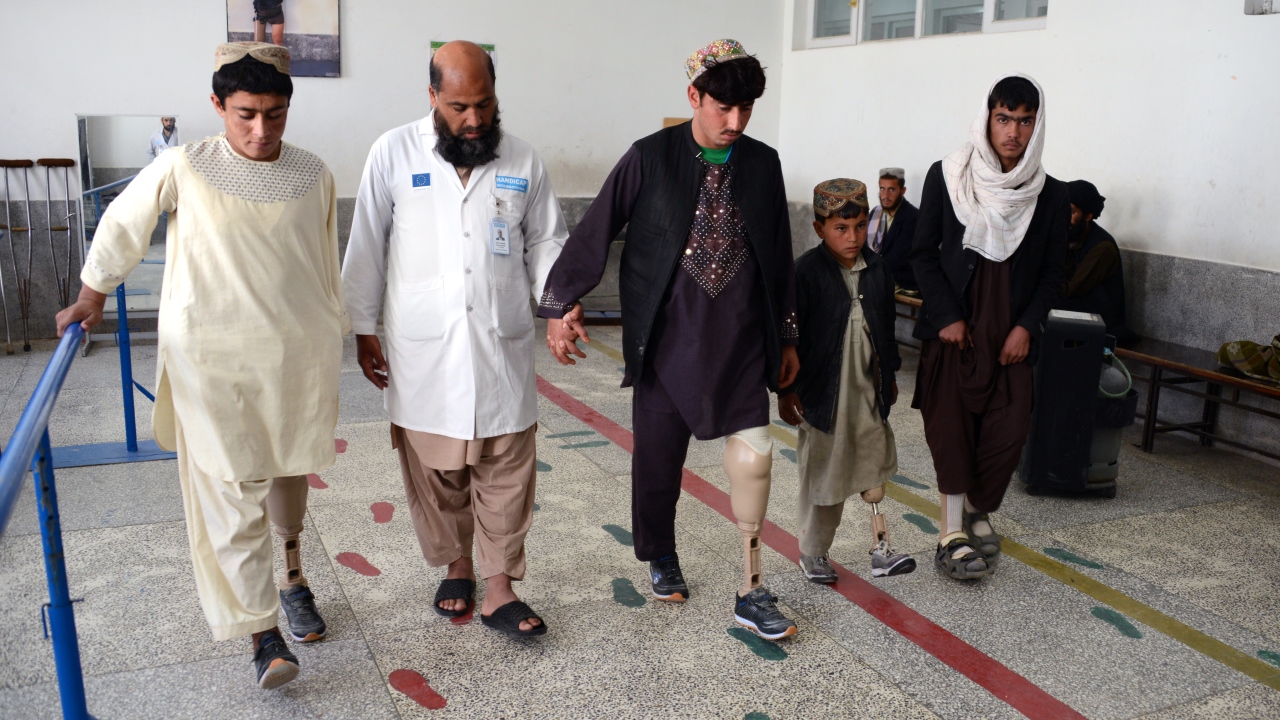 A physiotherapist from Kandahar Physical Rehabilitation Centre guiding the amputees during gait training process.; }}