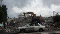 A car in front of building that have been destroyed and rubble that may contain explosive weapons. Gaza.; }}
