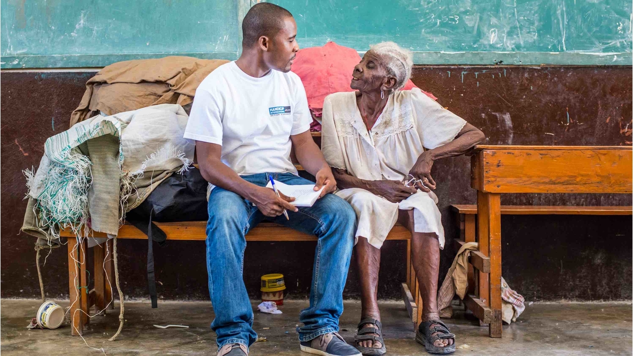 Handicap International's team with Méralia Simon, 90, who took refuge at Phillipe Guerrier secondary school, in les Cayes.; }}