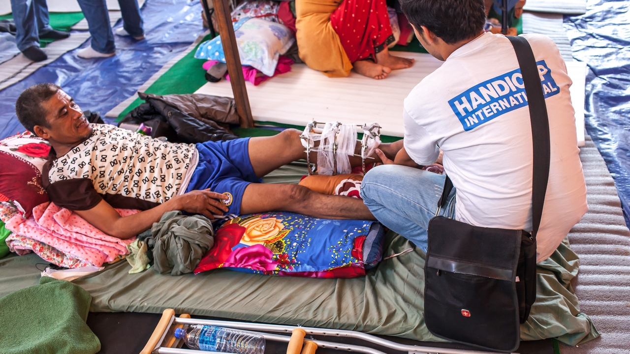 A Handicap International physiotherapist assesses an earthquake survivor with a fracture. Nepal; }}