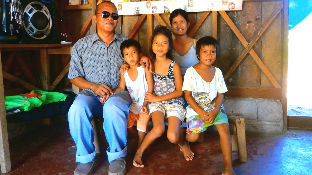 Renato, his wife and three of their six children in their newly repaired home. The Philippines.; }}