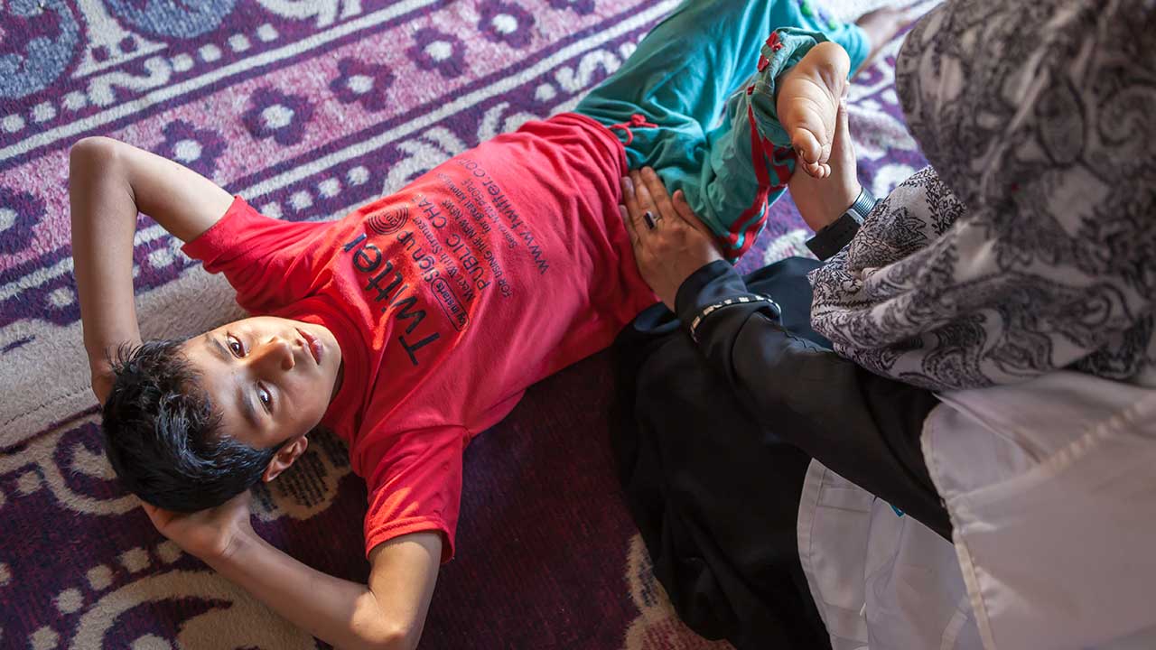Sahil, 10 years old, doing a rehabilitation session at home in Kashmir.; }}