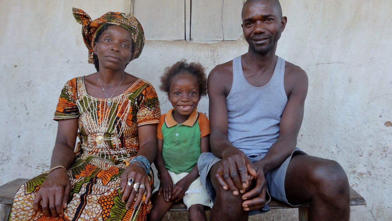 Eight-year-old Fanta, who has cerebral palsy, with her parents. Sierra Leone.; }}