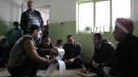Ali (right) with members of his family meeting one of Handicap International's case workers.; }}