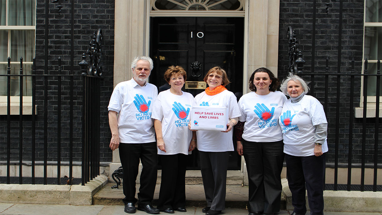 Campaigners at Downing Street (from left to right):  Martin Shirley of South Somerset Peace Group, Cathy Cotteridge, President of SI London Anglia, Barbara Brown of SI Darlington, Beatrice Cami, Head of Fundraising and Communication at Handicap International UK, and Heather Knott of SI Chelmsford.; }}