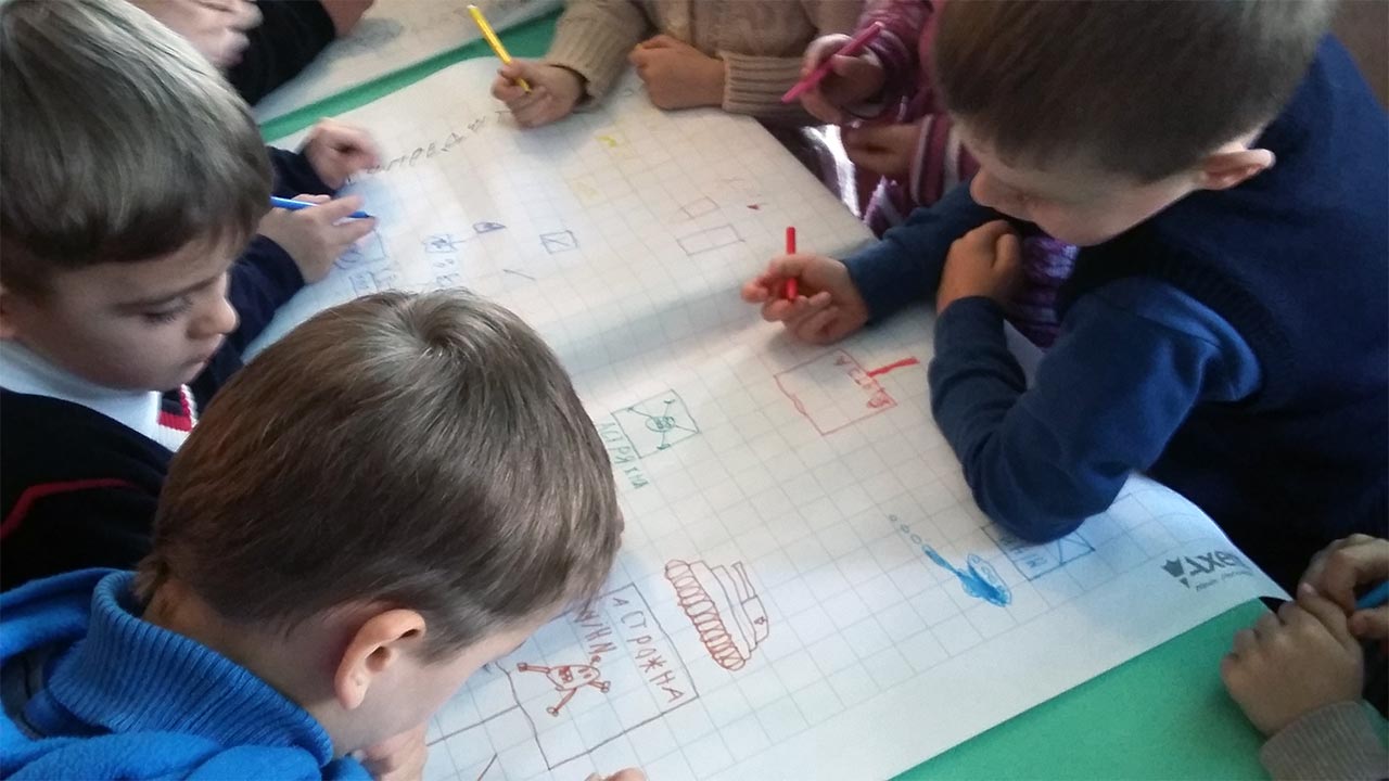 Children drawing situations where they might encounter mines, during a risk education session in Ukraine ; }}