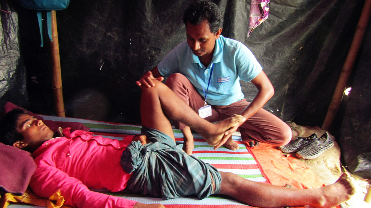 Abu Sadeq with an HI physiotherapist.; }}