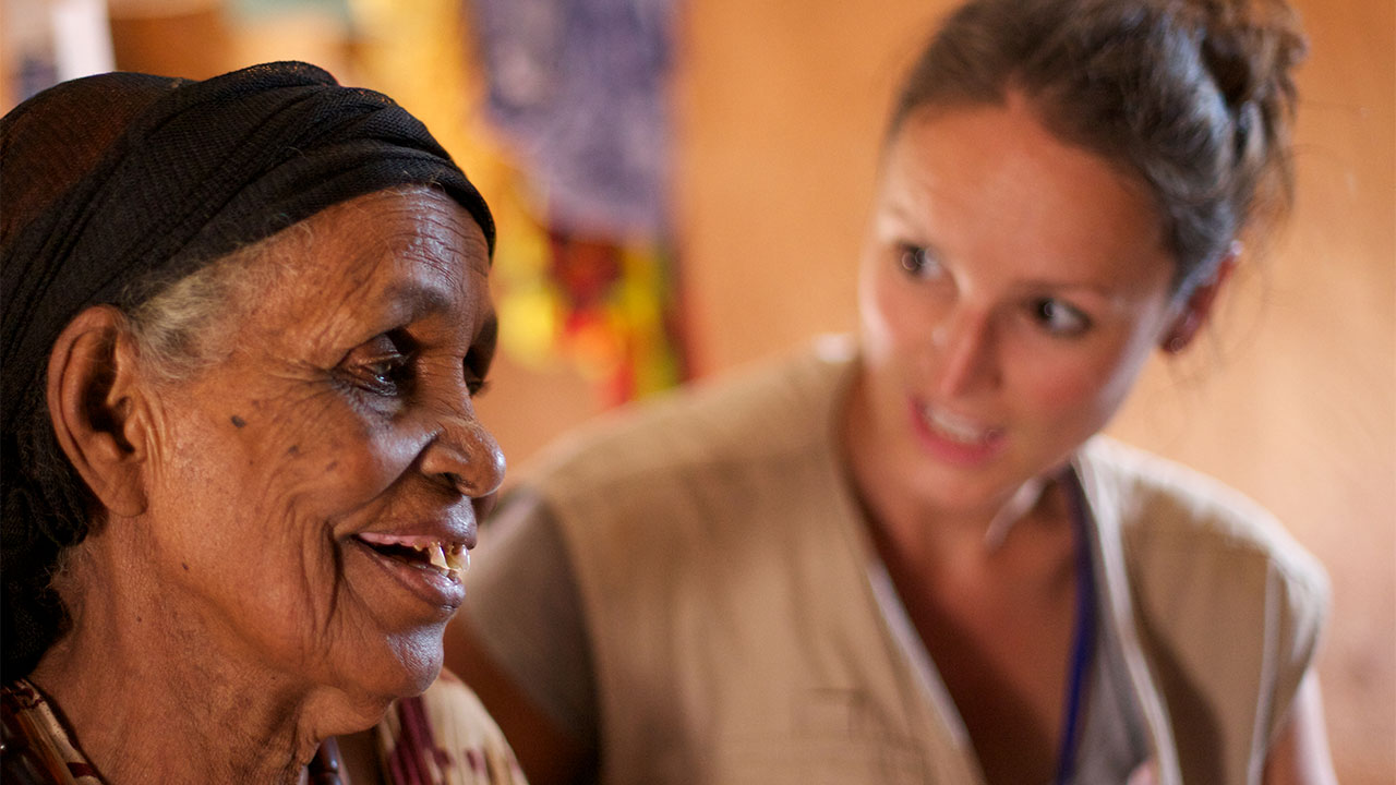 An HI physiotherapist laughing with an elderly woman.